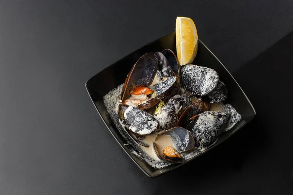 Baru dimasak kerang Seafood Shellfish dengan krim, anggur, saus keju dan lemon dalam mangkuk hitam, close-up, studio ditembak. Hidangan klasik di Belgia, Prancis dan Belanda. Restoran makanan. Horisontal — Stok Foto