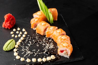 Somon, avokado, uçan balık havyarı, ton balığı ve krem peynirli suşi ruloları siyah tahtada izole. Somonlu Philadelphia suşisi. Suşi menüsü. Yatay fotoğraf.