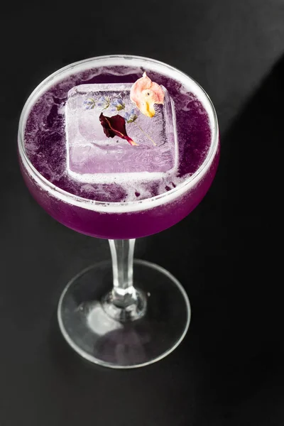 Homemade Purple Cocktail with a Large Ice Cube on black background. Close up of purple cocktails in a glass of margaritas with sugar edges, violet and protein foam. Vertical photo. — Stock Photo, Image