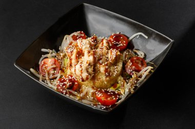 Tavuk, hindi, domates, buğday filizi ve unagi soslu kuskus tabağı siyah arka planda seçici odaklanma, üçte birini tabağa odakla. yatay