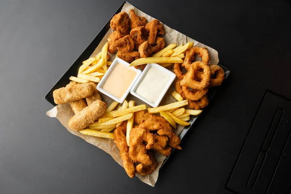 Atıştırmalık tabaklar - peynir çubukları, tavuk nugget, soğan halkaları, patates kroket karışımı aperatifler ve soslar. Bira tahtası. Yatay fotoğraf. Bar menüsü için fotoğraf