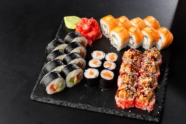 Various kinds of sushi served on black background. Sushi menu for Japanese food. Japanese sushi set. Rolls with tuna, salmon, shrimp, crab and avocado. Horizontal photo. — Stock Photo, Image