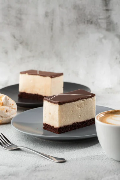 Pedaço de bolo com souffle Leite de pássaro, biscoito, mousse e chocolate escuro em um prato escuro, bolo de souffle branco. Menu para padaria. Menu de café. Deliciosa e doce sobremesa no restaurante café.Vertical — Fotografia de Stock