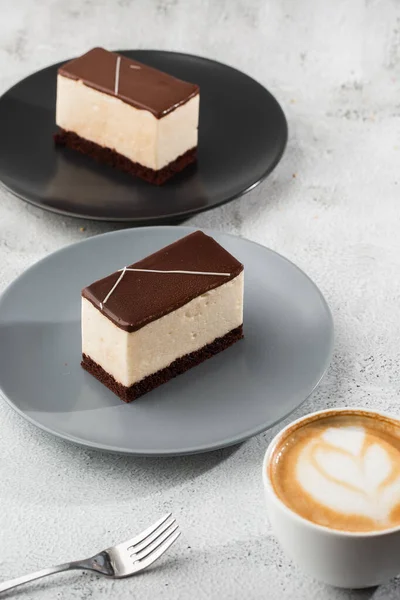 Pedaço de bolo com souffle Leite de pássaro, biscoito, mousse e chocolate escuro em um prato escuro, bolo de souffle branco. Menu para padaria. Menu de café. Deliciosa e doce sobremesa no restaurante café.Vertical — Fotografia de Stock