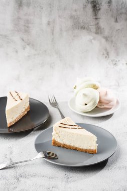 Cheesecake New York ya da beyaz masada bir fincan kahveli klasik cheesecake. Yakından bak. Lezzetli bir kahvaltı. Siyah tabakta bir parça kek, beyaz mermer arka planda beyaz bardak. Dikey fotoğraf.