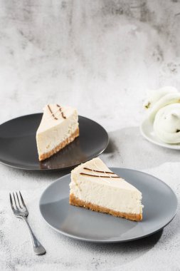 Cheesecake New York ya da beyaz masada bir fincan kahveli klasik cheesecake. Yakından bak. Lezzetli bir kahvaltı. Siyah tabakta bir parça kek, beyaz mermer arka planda beyaz bardak. Dikey fotoğraf.