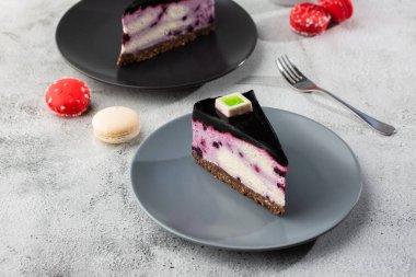 Böğürtlenli cheesecake ve beyaz masa üzerinde bir fincan kahve. Yakından bak. Lezzetli bir kahvaltı. Siyah tabakta bir parça kek, beyaz mermer arka planda beyaz bardak. Yatay fotoğraf.