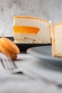 Hindistan cevizli, çarkıfelek meyveli, mangolu ve muzlu, çikolata jöleli zarif kek. Mermer zemin üzerinde turuncu katmanlı kek dilimi. Pasta kafesi ya da kafe menüsü için duvar kağıdı. dikey.