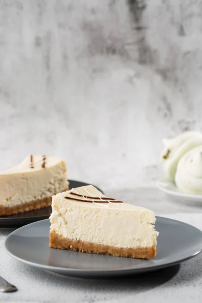 Cheesecake New York ya da beyaz masada bir fincan kahveli klasik cheesecake. Yakından bak. Lezzetli bir kahvaltı. Siyah tabakta bir parça kek, beyaz mermer arka planda beyaz bardak. Dikey fotoğraf.
