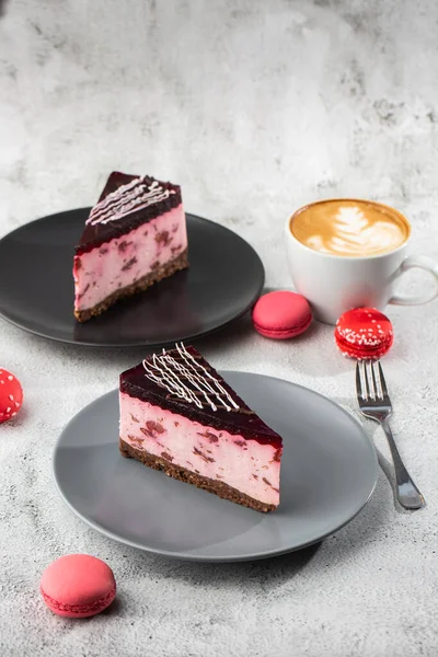 Kirazlı cheesecake ve beyaz masa üzerinde bir fincan kahve. Yakından bak. Lezzetli bir kahvaltı. Siyah tabakta bir parça kek, beyaz mermer arka planda beyaz bardak. Dikey fotoğraf.