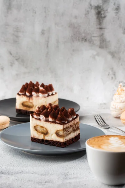 Tiramisu - desert clasic cu mascarpone si cafea. Tort delicios Tiramisu pe o placă întunecată pe un fundal de marmură deschisă. Fotografie verticală . — Fotografie, imagine de stoc