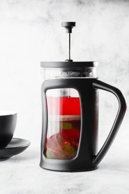 French press 'te yaban mersini, kırmızı ya da ahududu çayı ve parlak mermer arka planda koyu fincanı var. Genel görünüm, kopyalama alanı. Kafe menüsü reklamı. Kahve dükkanı menüsü. Dikey fotoğraf.