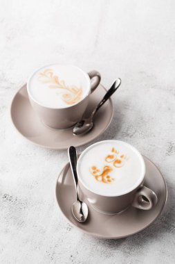 Parlak mermer arka planda izole edilmiş iki beyaz fincan sütlü latte kahve. Genel görünüm, kopyalama alanı. Kafe menüsü reklamı. Kahve dükkanı menüsü. Dikey pho