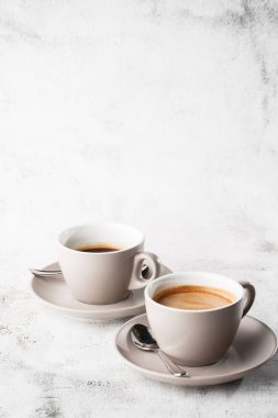 Parlak mermer zemin üzerinde izole edilmiş sütlü, iki beyaz fincan sade kahve. Genel görünüm, kopyalama alanı. Kafe menüsü reklamı. Kahve dükkanı menüsü. Dikey fotoğraf.