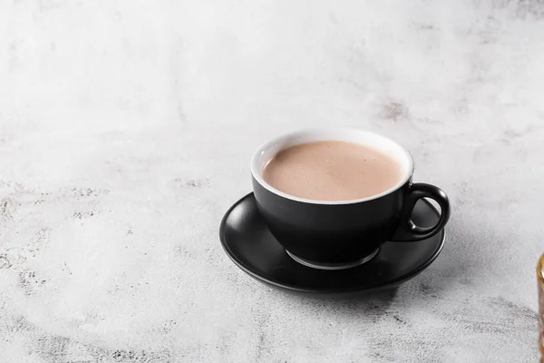 Cup of hot cocoa or hot chocolate in dark cup isolated on bright marble background. Overhead view, copy space. Advertising for cafe menu. Coffee shop menu. Horizontal photo. traditional drinks for win