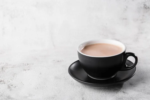 Cup of hot cocoa or hot chocolate in dark cup isolated on bright marble background. Overhead view, copy space. Advertising for cafe menu. Coffee shop menu. Horizontal photo. traditional drinks for win