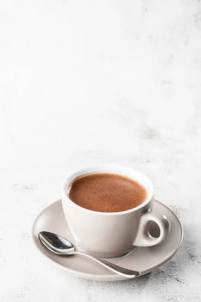 Cup of hot cocoa or hot chocolate or americano in white cup isolated on bright marble background. Overhead view, copy space. Advertising for cafe menu. Coffee shop menu. Vertical photo. traditional dr