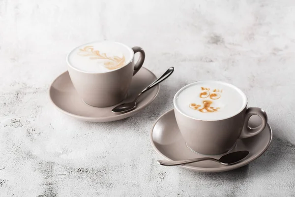 Två vita koppar varmt latte kaffe med vacker mjölk skum latte konst konsistens isolerad på ljus marmor bakgrund. Overhead view, kopiera utrymme. Reklam för cafémenyn. Kafémenyn. Övergripande p — Stockfoto