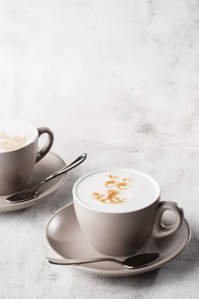 Две белые чашки горячего кофе латте с красивой текстурой латте молока, выделенные на ярком мраморном фоне. Вид сверху, место для копирования. Реклама меню кафе. Меню кафе. Вертикальная фо — стоковое фото