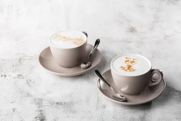 Duas xícaras brancas de café quente com latte de espuma de leite bonito textura arte latte isolado em fundo de mármore brilhante. Visão geral, espaço de cópia. Publicidade para menu de café. Menu da cafetaria. Horizontal p — Fotografia de Stock