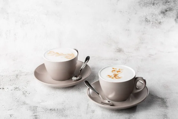 Two white cups of hot latte coffee with beautiful milk foam latte art texture isolated on bright marble background. Overhead view, copy space. Advertising for cafe menu. Coffee shop menu. Horizontal p