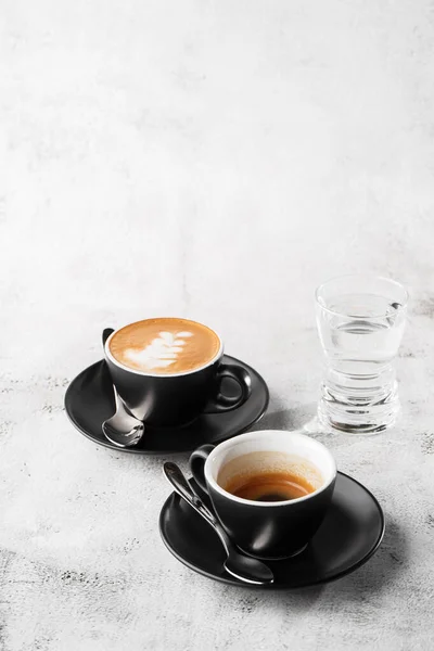 Due tazze scure di caffè nero caldo, espresso, cappuccino con latte isolato su fondo marmo brillante. Vista aerea, copiare spazio. Pubblicità per il menu del caffè. Menù della caffetteria. Foto verticale . — Foto Stock