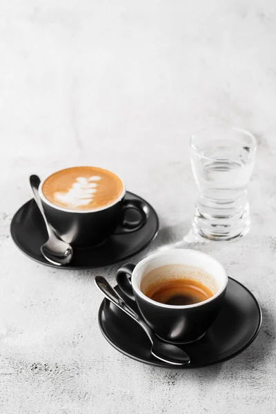 Duas xícaras escuras de café preto quente, café expresso, cappuccino com leite isolado em fundo de mármore brilhante. Visão geral, espaço de cópia. Publicidade para menu de café. Menu da cafetaria. Foto vertical . — Fotografia de Stock