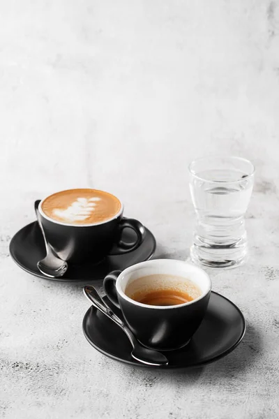 Duas xícaras escuras de café preto quente, café expresso, cappuccino com leite isolado em fundo de mármore brilhante. Visão geral, espaço de cópia. Publicidade para menu de café. Menu da cafetaria. Foto vertical . — Fotografia de Stock