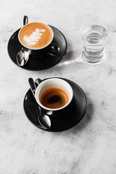 Две темные чашки горячего черного кофе, эспрессо, капучино с молоком изолированы на ярком мраморном фоне. Вид сверху, место для копирования. Реклама меню кафе. Меню кафе. Вертикальное фото . — стоковое фото