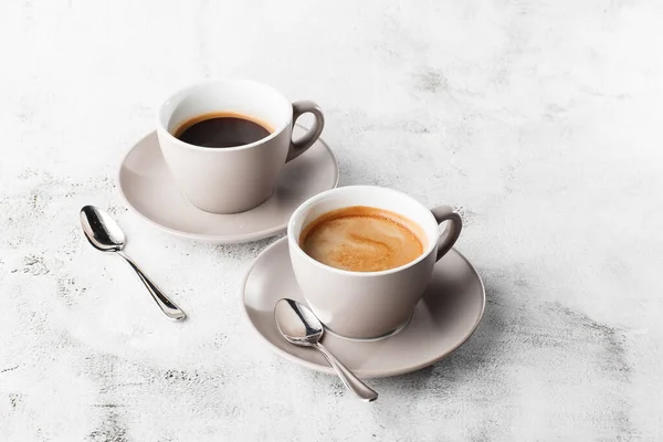 Två vita koppar varmt svart kaffe med mjölk isolerad på ljus marmor bakgrund. Overhead view, kopiera utrymme. Reklam för cafémenyn. Kafémenyn. Horisontellt foto. — Stockfoto