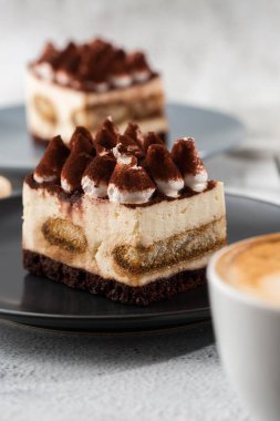 Tiramisu, mascarpone ve kahveli klasik tatlı. Hafif mermer arka planda koyu bir tabakta nefis bir Tiramisu keki. Dikey fotoğraf.