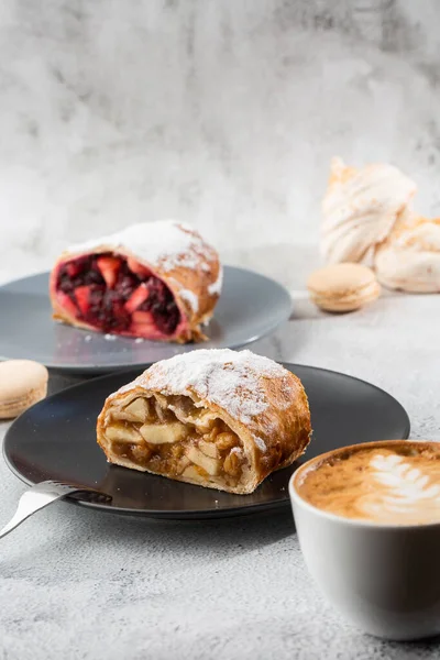 Strudel traditionnel autrichien aux pommes fraîches, aux noix et au sucre en poudre. Menu pour café. Pièce de gâteau sur plaque noire, tasse blanche sur fond de marbre blanc. Photo verticale . — Photo