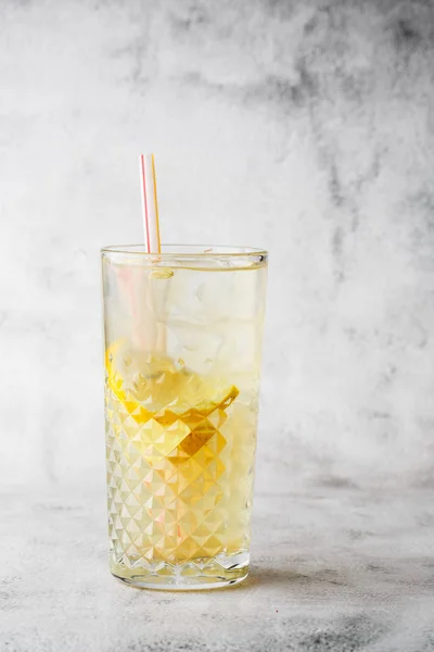Glass with lemonade with lemon, cold refreshing drink or beverage with ice on bright marble background. Overhead view, copy space. Advertising for cafe menu. Vertical photo. — Stock Photo, Image