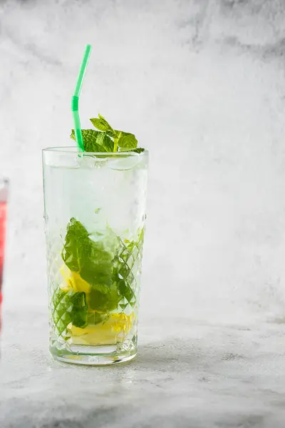 Glass with classic mojito cocktail with lemon and mint, cold refreshing drink or beverage with ice on bright marble background. Overhead view, copy space. Advertising for cafe menu. Vertical photo. — Stock Photo, Image