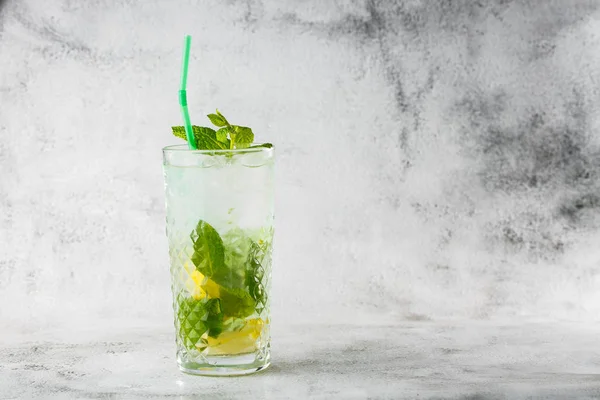 Glass with classic mojito cocktail with lemon and mint, cold refreshing drink or beverage with ice on bright marble background. Overhead view, copy space. Advertising for cafe menu. Horizontal photo. — Stock Photo, Image