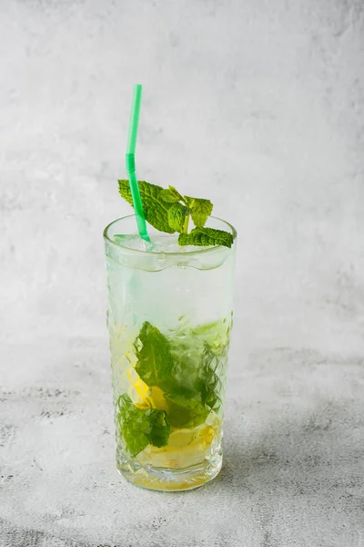 Glass with classic mojito cocktail with lemon and mint, cold refreshing drink or beverage with ice on bright marble background. Overhead view, copy space. Advertising for cafe menu. Vertical photo. — Stock Photo, Image