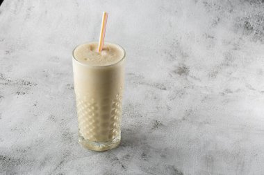 Muzlu yulaf püresi ya da parlak mermer arka planda bardakta vanilyalı milkshake. Genel görünüm, kopyalama alanı. Milkshake kafe menüsü reklamı. Yatay fotoğraf.