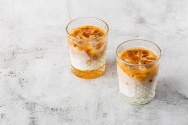 Işıl ışıl mermer zemin üzerinde soğuk kahve ve süt ile izole edilmiş iki bardak. Genel görünüm, kopyalama alanı. Kafe menüsü reklamı. Kahve dükkanı menüsü. Yatay fotoğraf.