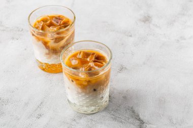 Işıl ışıl mermer zemin üzerinde soğuk kahve ve süt ile izole edilmiş iki bardak. Genel görünüm, kopyalama alanı. Kafe menüsü reklamı. Kahve dükkanı menüsü. Yatay fotoğraf.