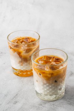 Işıl ışıl mermer zemin üzerinde soğuk kahve ve süt ile izole edilmiş iki bardak. Genel görünüm, kopyalama alanı. Kafe menüsü reklamı. Kahve dükkanı menüsü. Dikey fotoğraf.