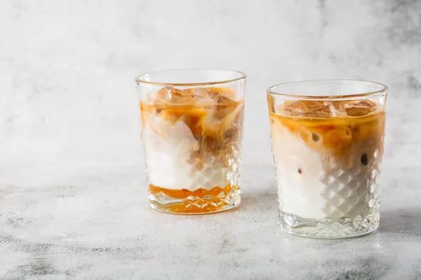 Two glasses with cold brew coffee and milk isolated on bright marble background. Overhead view, copy space. Advertising for cafe menu. Coffee shop menu. Horizontal photo.