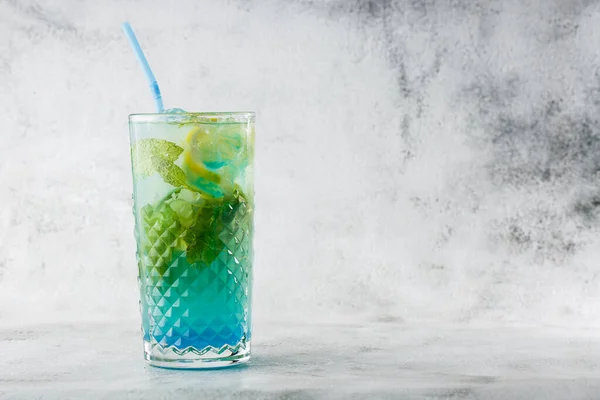 Blue cocktail with ice cubes and slices of lemon and lime. Blue lagoon summer coctail. Iced blue lemonade. Overhead view, copy space. Advertising for cafe. Bar menu. Vertical photo. — Stock Photo, Image