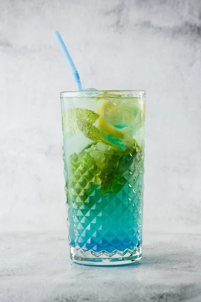 Blue cocktail with ice cubes and slices of lemon and lime. Blue lagoon summer coctail. Iced blue lemonade. Overhead view, copy space. Advertising for cafe. Bar menu. Vertical photo.