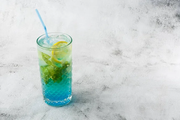 Blue cocktail with ice cubes and slices of lemon and lime. Blue lagoon summer coctail. Iced blue lemonade. Overhead view, copy space. Advertising for cafe. Bar menu. Horizontal photo. — Stock Photo, Image