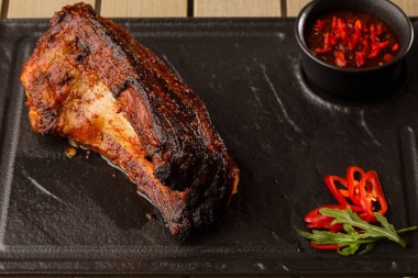 Izgara ve barbekü sıcak domuz kaburga sıcak biber ve siyah taş arka plan üzerinde sıcak sos ile. Izole. Erkekler için yemek. Baharatlı