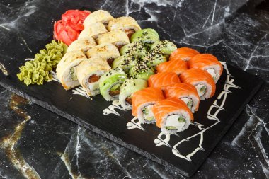 Siyah mermer arka planda servis edilen çeşitli suşiler. Japon yemeği için suşi menüsü. Japon suşi seti. Ton balığı, somon, karides, yengeç, havyar ve avokado. Yatay fotoğraf.