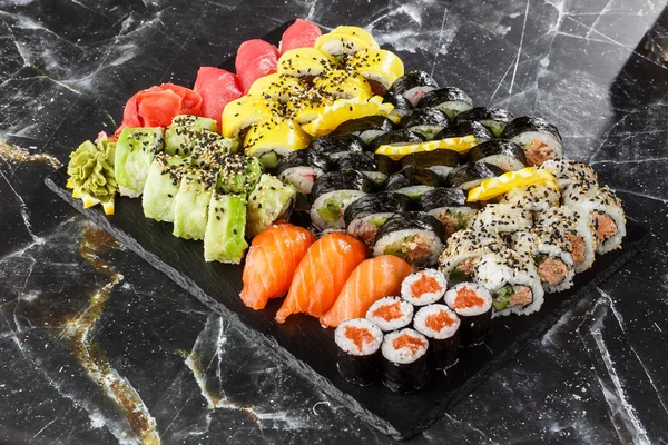 Japanese sushi set. Set of fresh tuna maki , salmon nigiri and dragon sushi rolls served on black plate close-up. Horizontal top view from above Top view flat lay. A set for a large company.