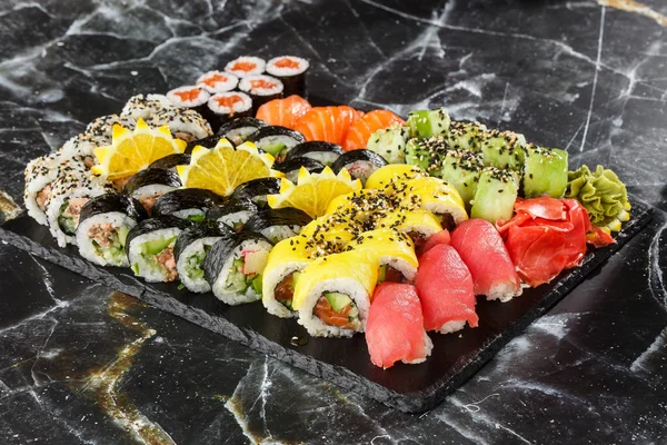 Japanese sushi set. Set of fresh tuna maki , salmon nigiri and dragon sushi rolls served on black plate close-up. Horizontal top view from above Top view flat lay. A set for a large company.