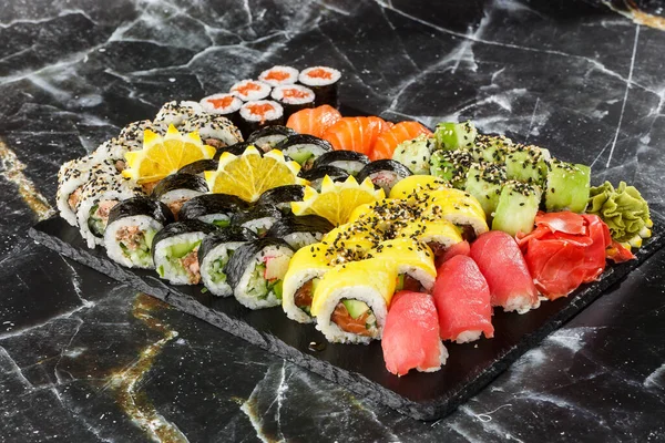 Japanese sushi set. Set of fresh tuna maki , salmon nigiri and dragon sushi rolls served on black plate close-up. Horizontal top view from above Top view flat lay. A set for a large company.