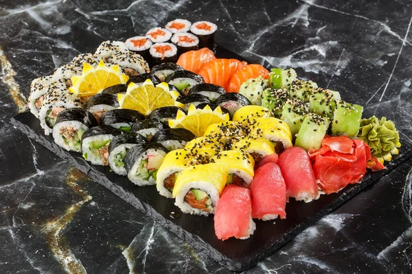 Japanese sushi set. Set of fresh tuna maki , salmon nigiri and dragon sushi rolls served on black plate close-up. Horizontal top view from above Top view flat lay. A set for a large company.